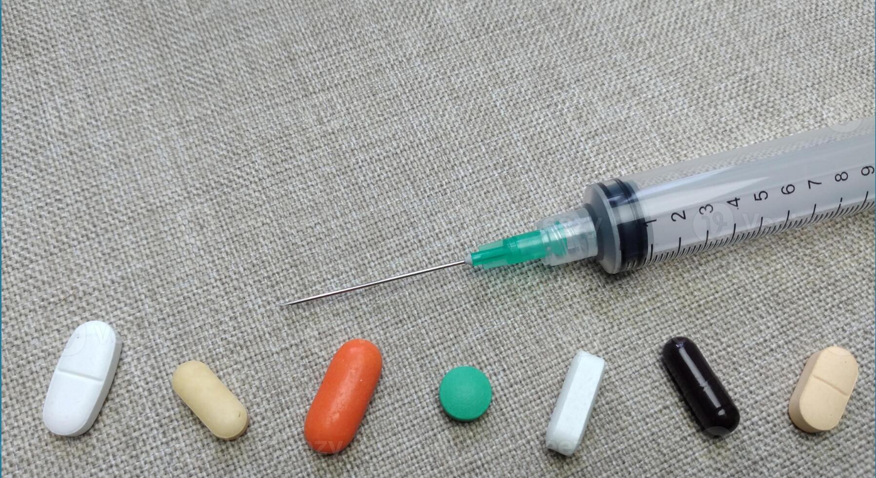 Medicine pills of various kinds and types with injections on a cloth background photo