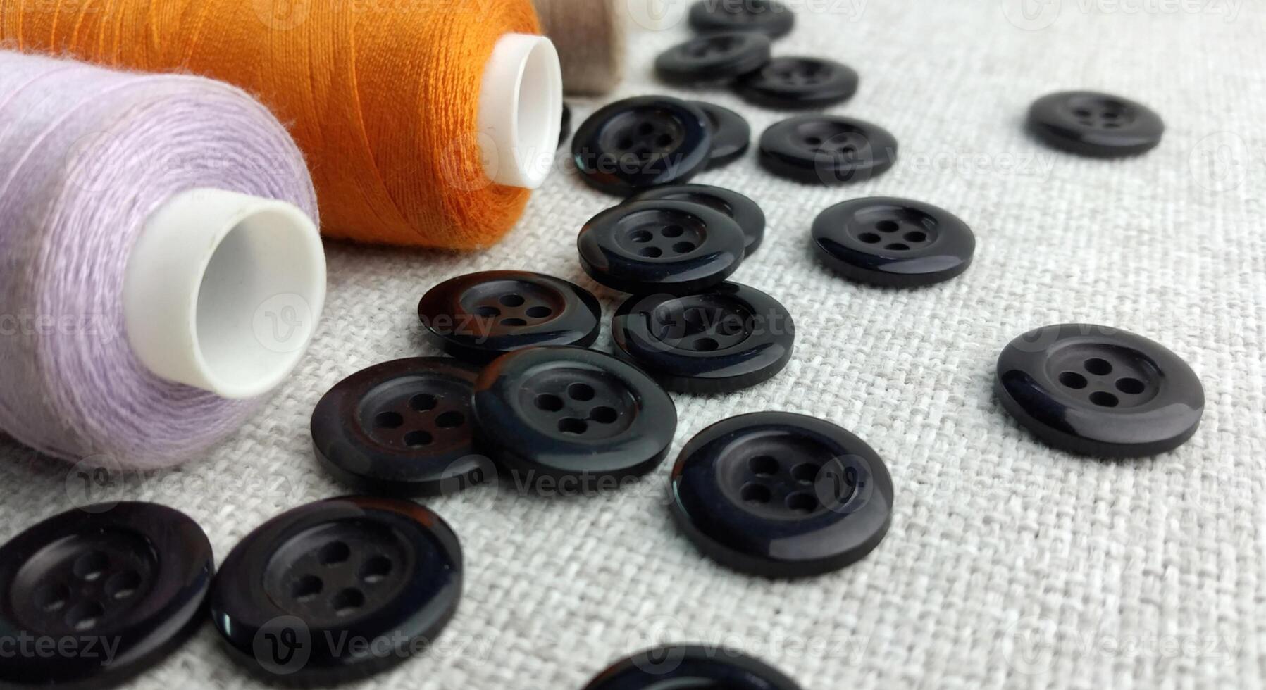 Spools of thread and buttons on a gray background, top view photo