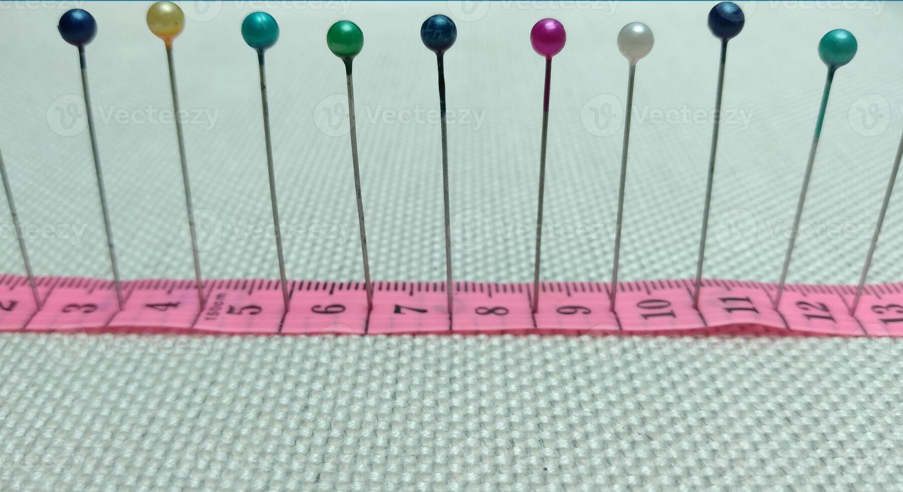 sewing needles and pins of different colors, ruler on white cloth background photo