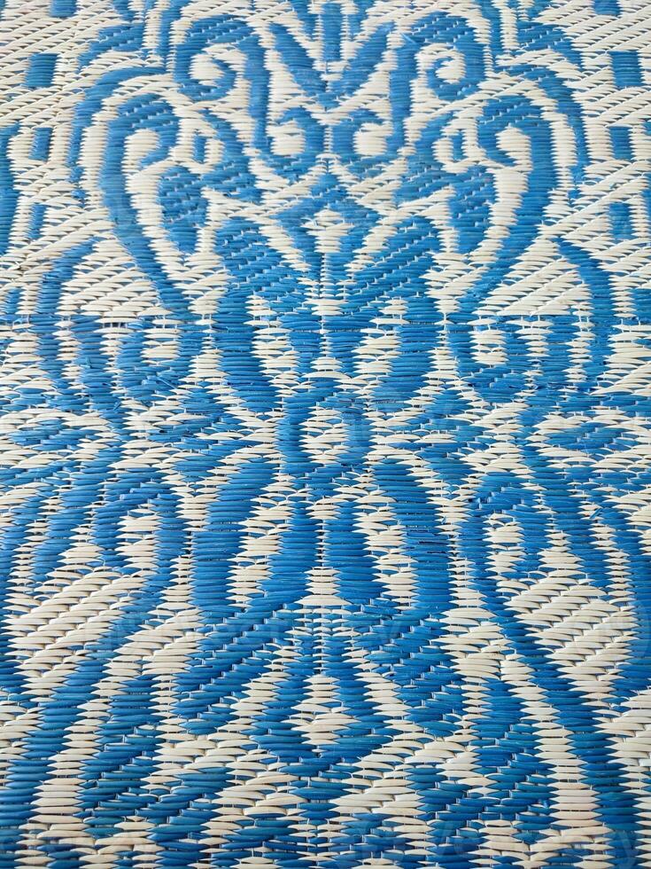 Blue and white woven mat with motif designs on it photo