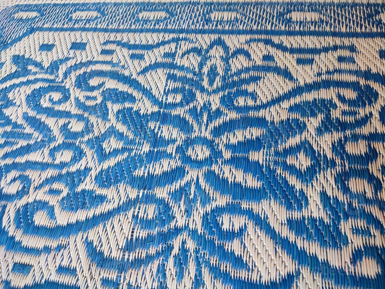 Blue and white woven mat with motif designs on it photo