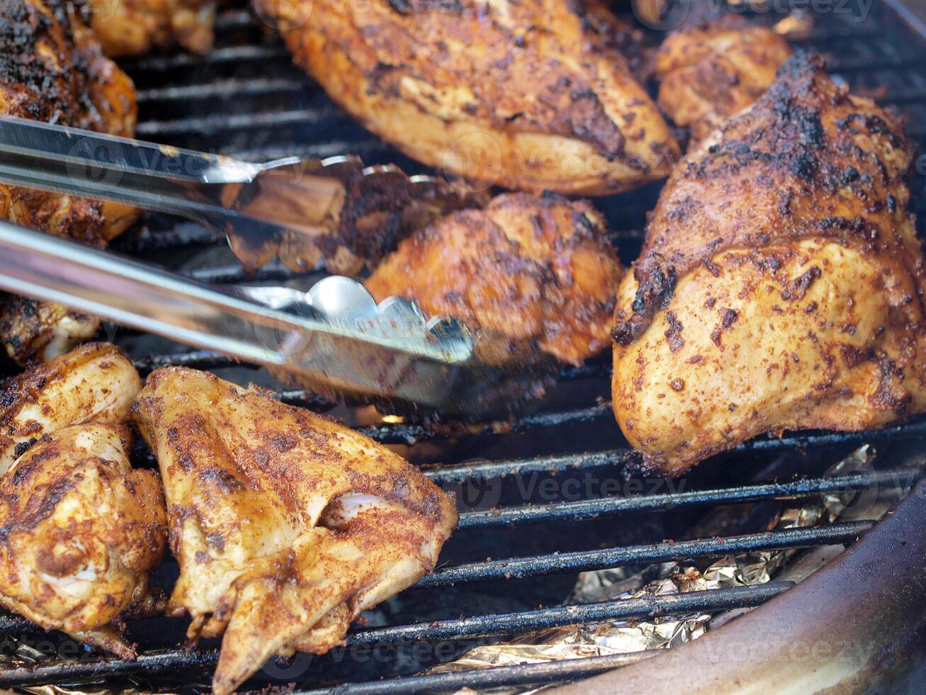 bar-b-que chicken on the grill with tongs photo
