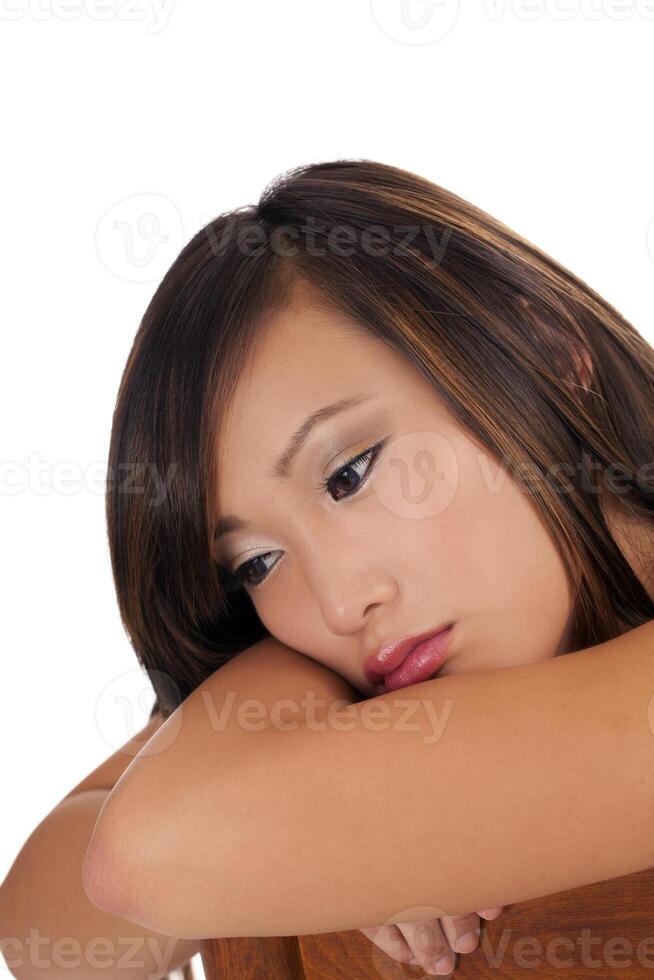 Sad looking Asian teen girl head on arms photo