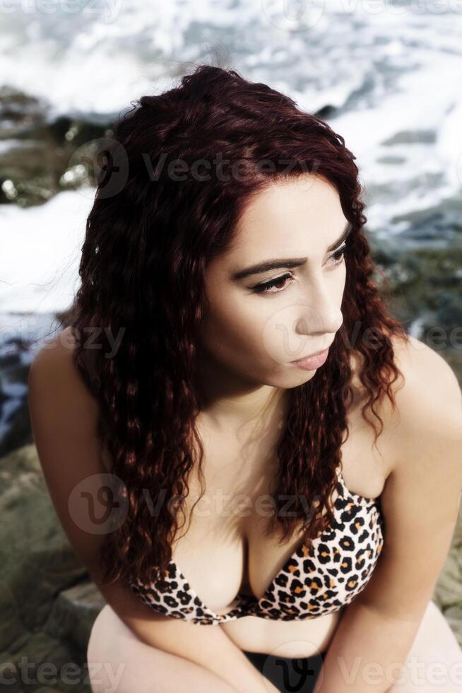 Latina Woman Sitting On Rocks With Bikini Sea Background photo