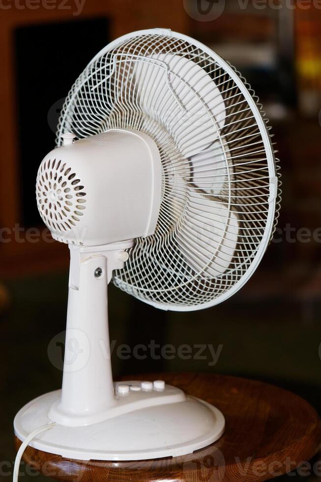 White Electric Fan Sitting On Stool From Back photo