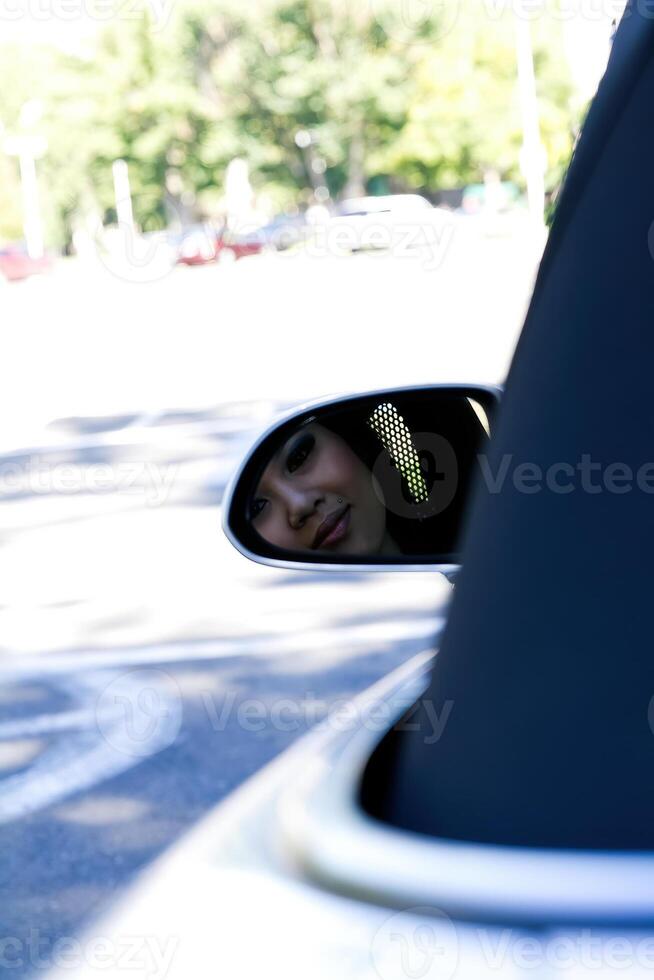 asiático americano mujer reflejado en lado ver espejo en coche foto