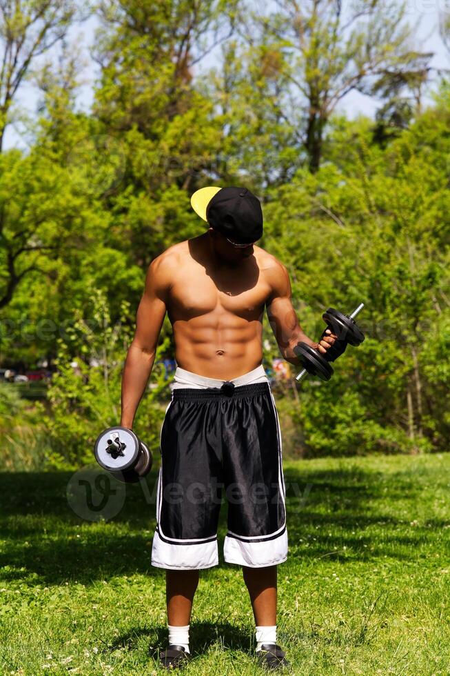 African American Man Lifting Weights Outdoors At Park photo