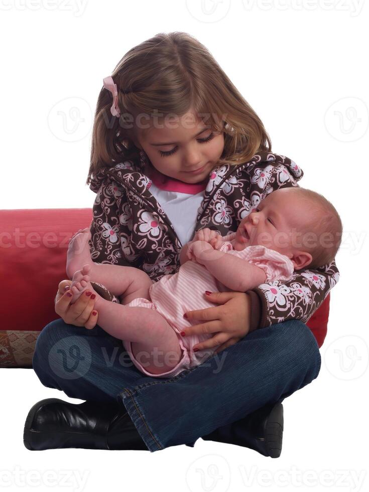 joven caucásico niña participación infantil hermana en su regazo foto