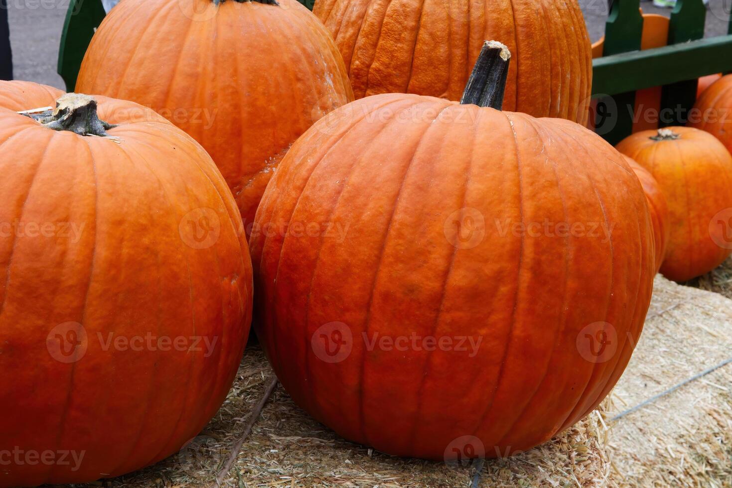 Several Orange Pumpkins Sitting On Bales Of Hay photo