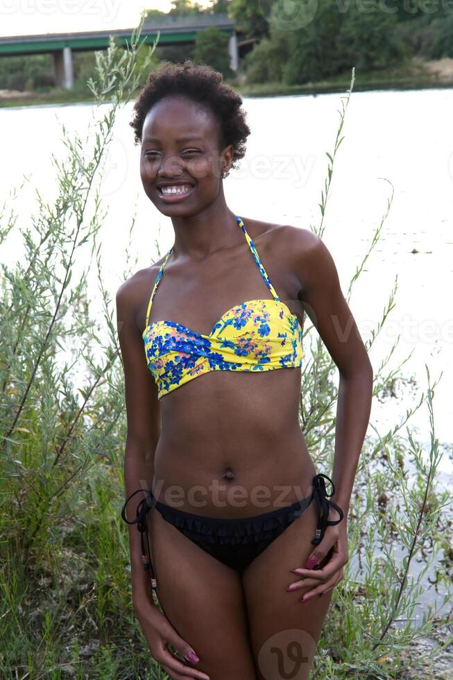joven africano americano adolescente mujer nadar traje a río foto
