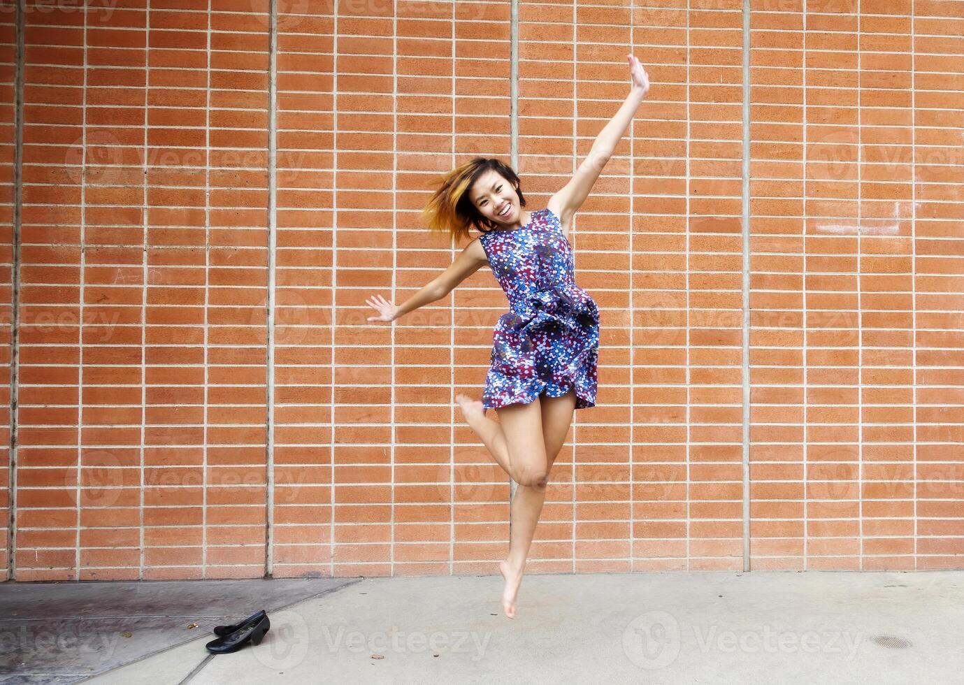 Smiling Asian American Woman Jumping In Dress photo