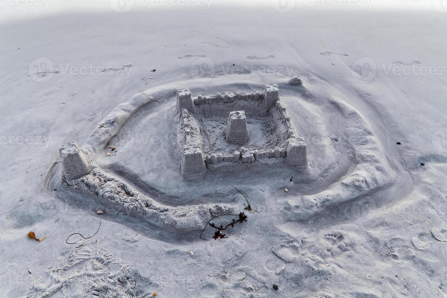 Sand Castle On Beach Eroded By Returning Water With Foot Prints photo