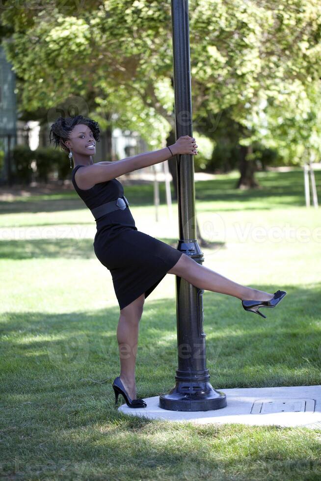 Young black woman in dress holdig on to pole photo