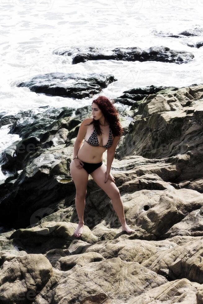 Latina Woman Standing On Rocks In Bikini With Water photo