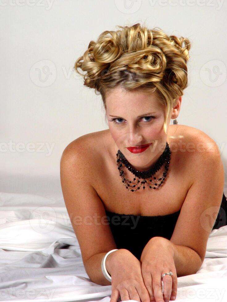 Caucasian Blond Woman In Black Dress On White Sheet photo