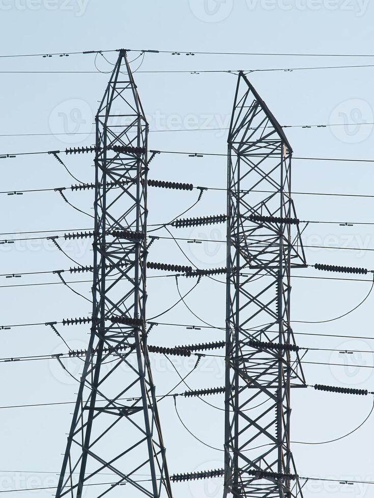Two Metal High Voltage Power Towers Against Blue Sky photo