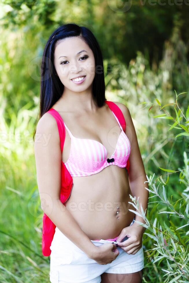 Smiling Skinny Asian American Woman Undressing Outdoors photo