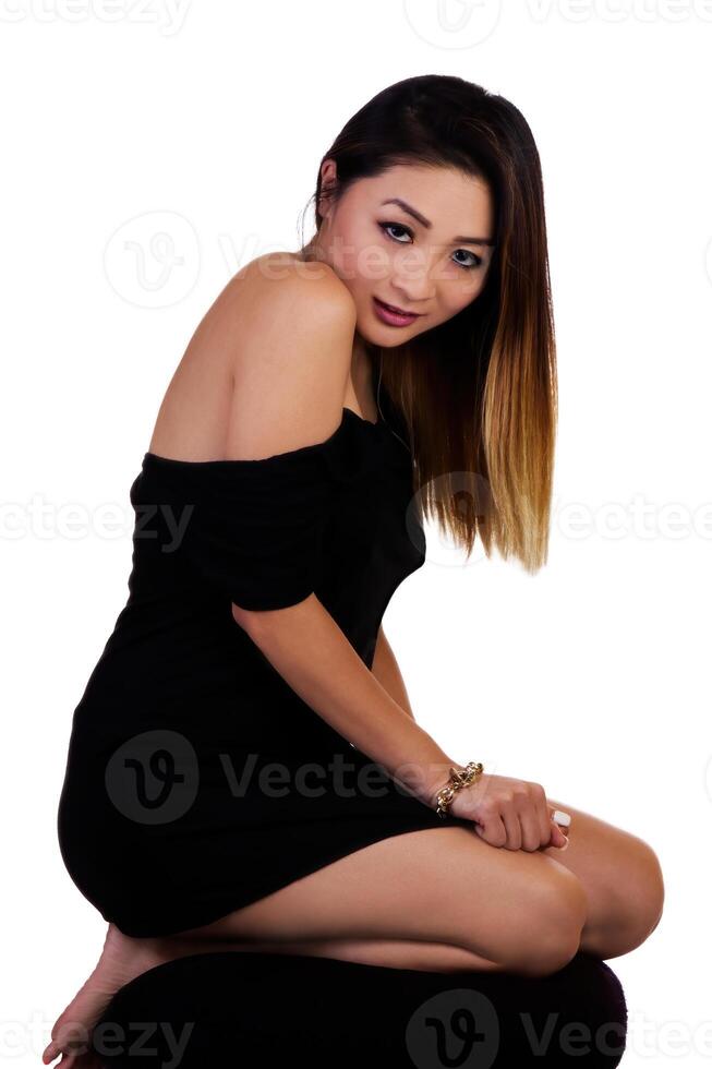 Attractive Asian American Woman Kneeling In Black Dress On White photo