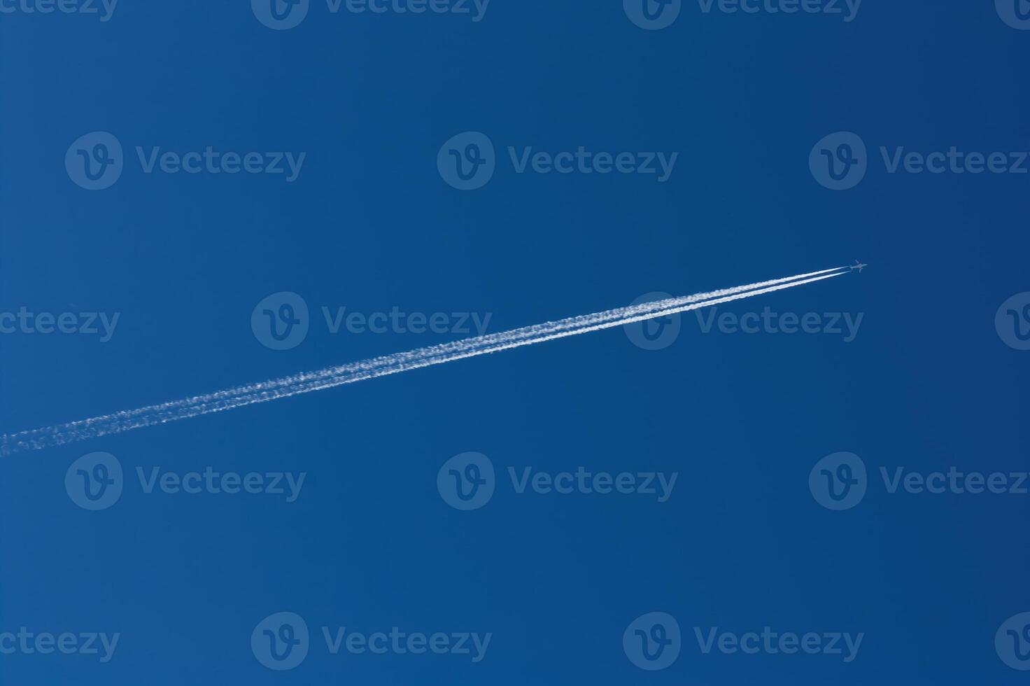 Jet With Ice Trail Streaming Behind In Blue Sky photo