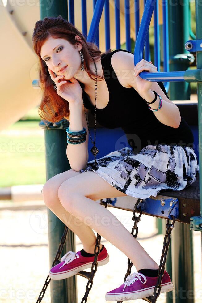 Young teen girl in skirt on playground equipment photo