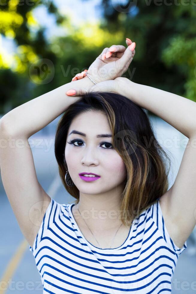 asiático americano mujer al aire libre retrato brazos en cabeza foto