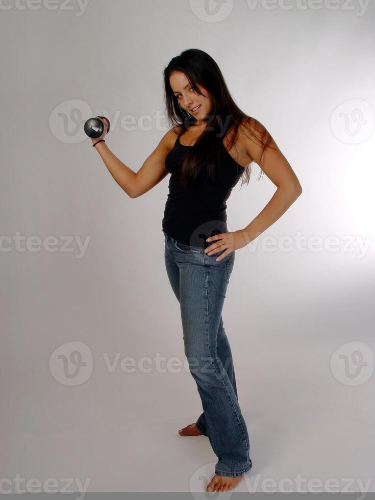 caucásico mujer participación pequeño peso en azul pantalones y negro parte superior foto