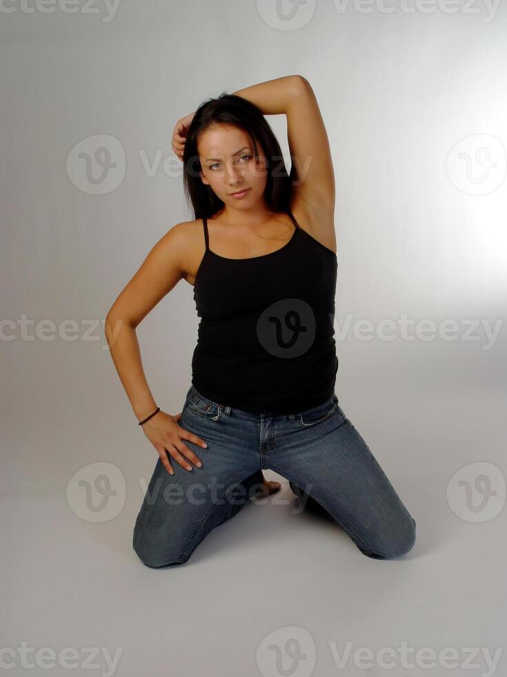 Caucasian Woman Kneeling In Blue Jeans And Black Top photo