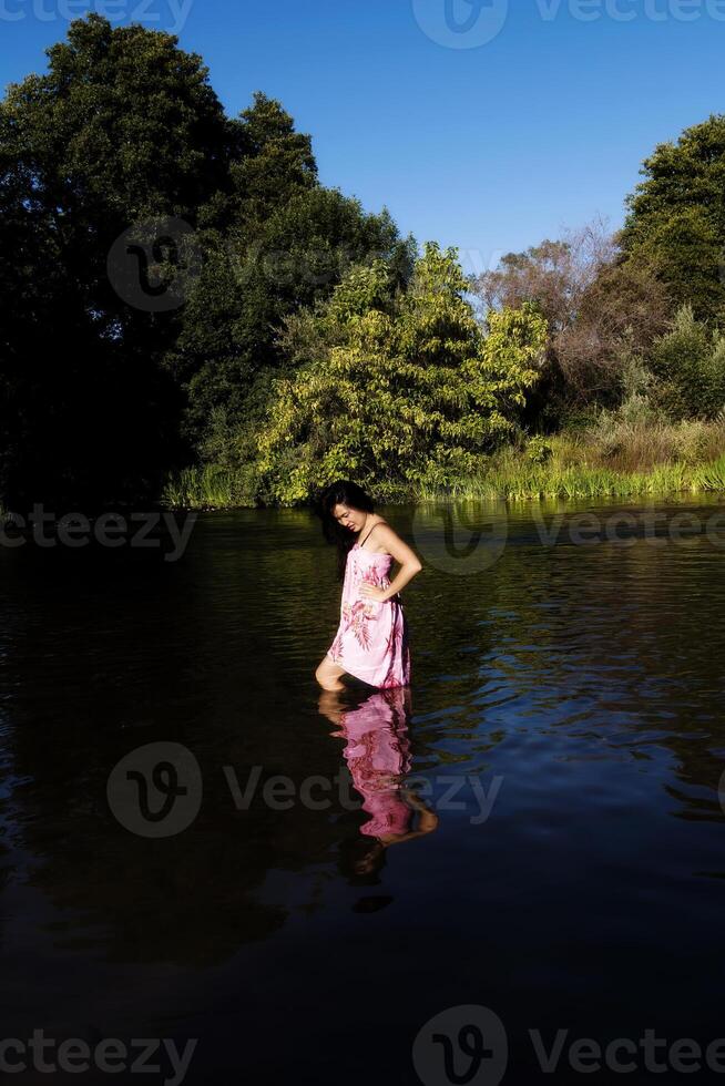 joven japonés americano mujer en pie en río foto