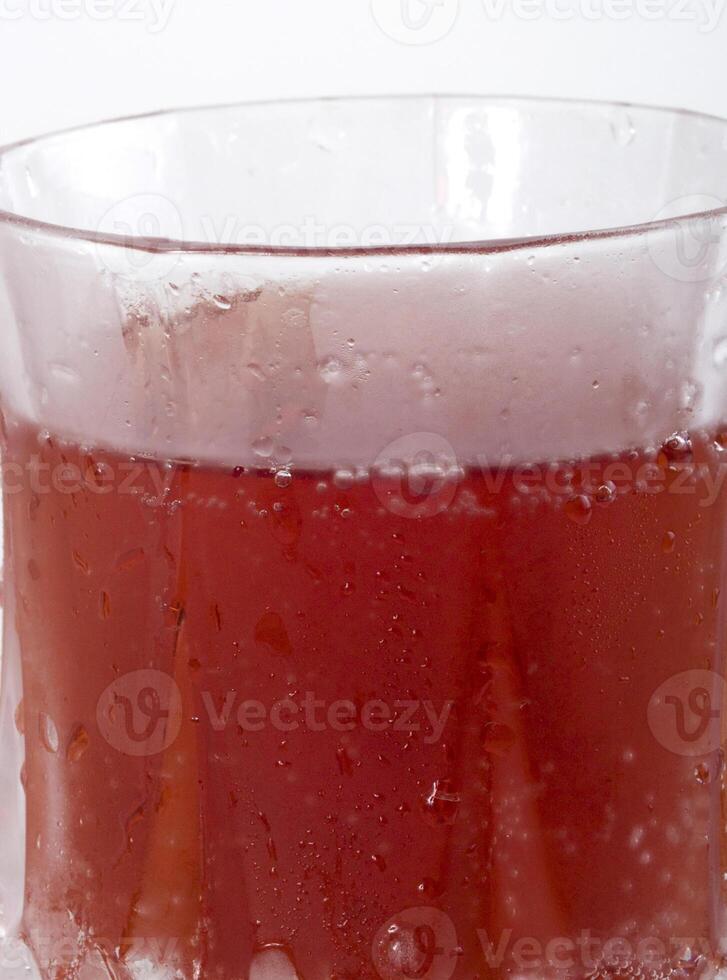 Red carbonated drink in frosted crystal glass closeup photo