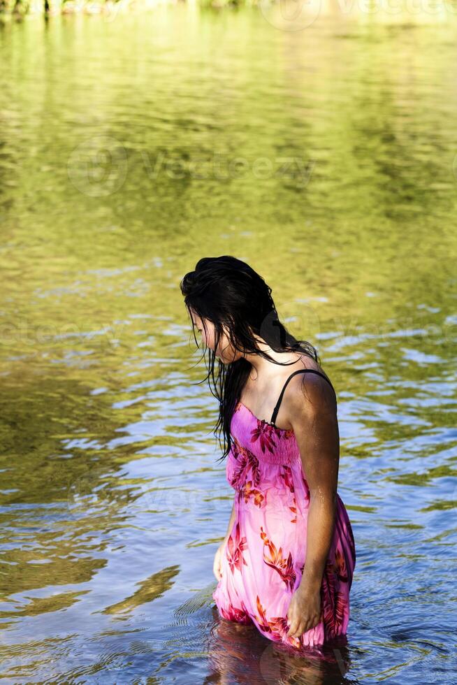 joven japonés americano mujer en pie en río mojado foto