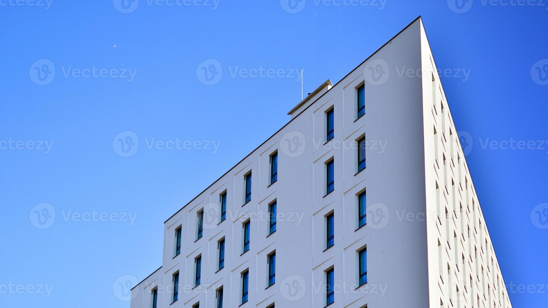 View of a white modern apartment building. Perfect symmetry with blue sky. Geometric architecture detail modern concrete structure building. Abstract concrete architecture. photo