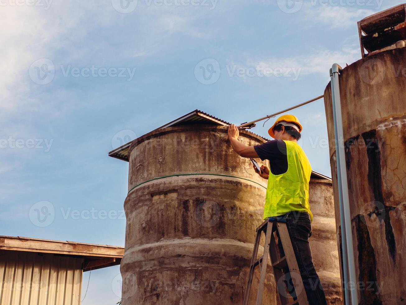 ingeniero que controla la calidad del agua se encuentra en las escaleras de riesgo en lugares altos operando equipos de filtración o purificación de agua industrial viejos tanques de cemento para mantener el agua en la fábrica de agua foto