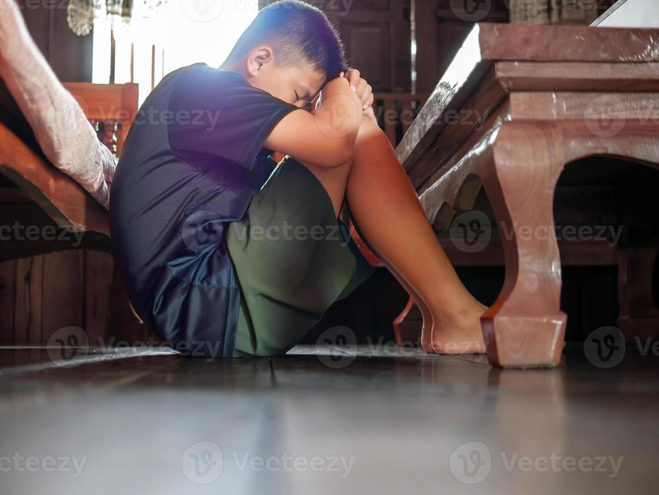 Asian kid boy Upset, sitting in the dark, thinking about conflicts, family relationships. sad face, Unhappy child sitting with head down, Emotion sad and sad face, depression children concept photo