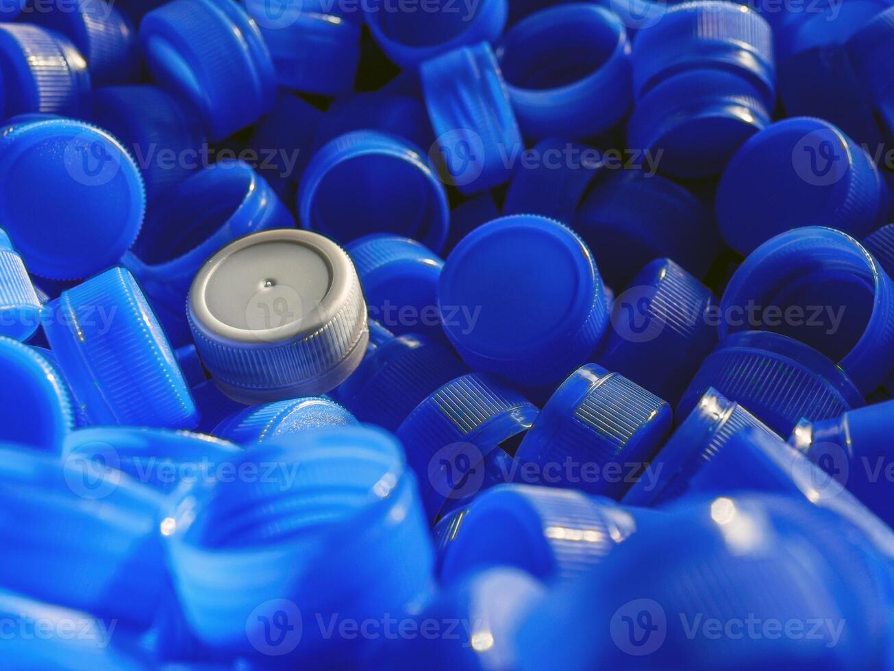 Grey plastic bottle caps on top to depict the concept of standing out from the crowd, dare to be different, odd man out, success or a leadership concept. photo