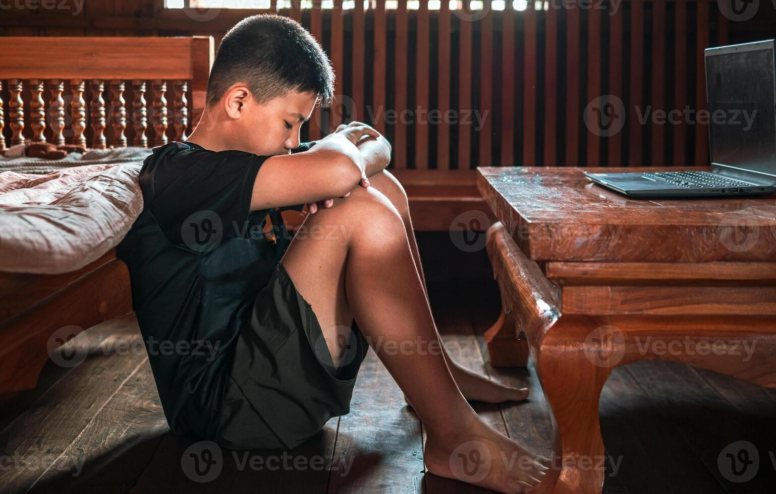 Asian kid boy Upset, sitting in the dark, thinking about conflicts, family relationships. sad face, Unhappy child sitting with head down, Emotion sad and sad face, depression children concept photo