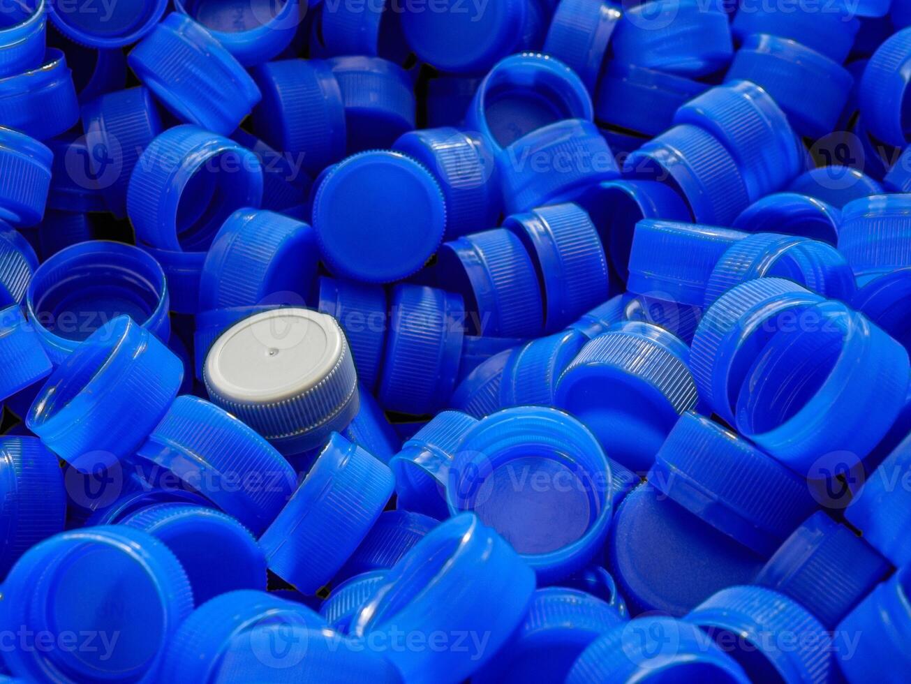 Grey plastic bottle caps on top to depict the concept of standing out from the crowd, dare to be different, odd man out, success or a leadership concept. photo