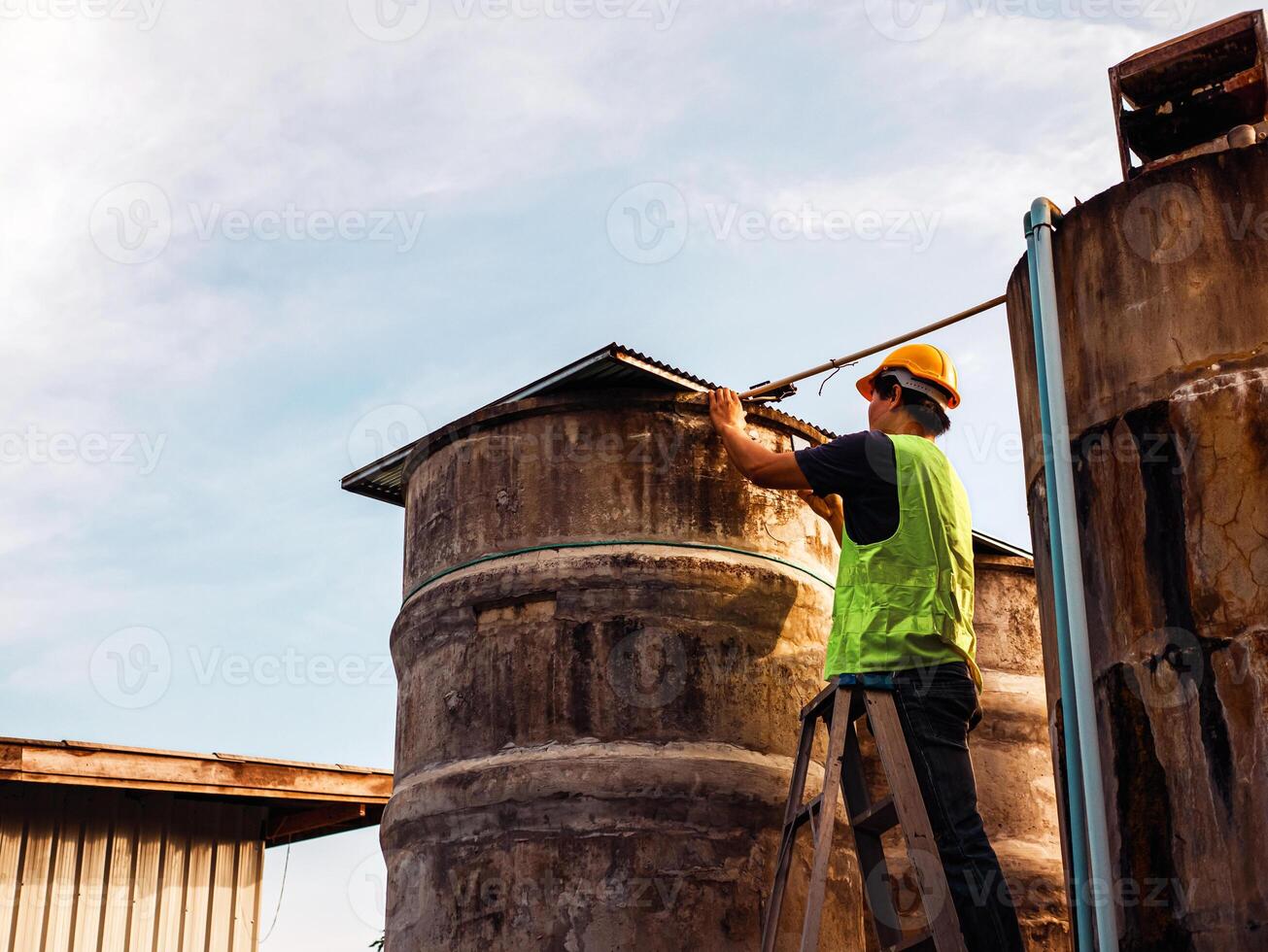 ingeniero que controla la calidad del agua se encuentra en las escaleras de riesgo en lugares altos operando equipos de filtración o purificación de agua industrial viejos tanques de cemento para mantener el agua en la fábrica de agua foto