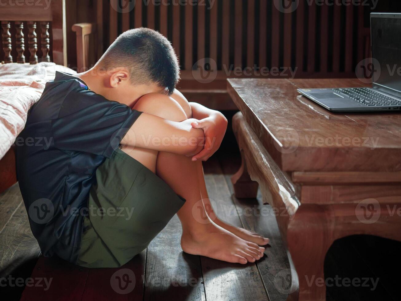 Asian kid boy Upset, sitting in the dark, thinking about conflicts, family relationships. sad face, Unhappy child sitting with head down, Emotion sad and sad face, depression children concept photo