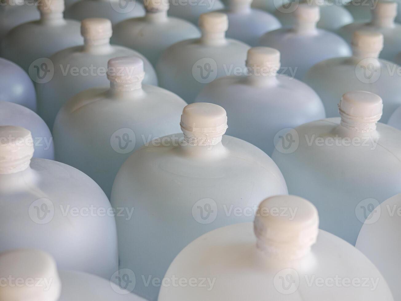 Many white gallons of drinking water are lined up in a drinking water production plant. photo