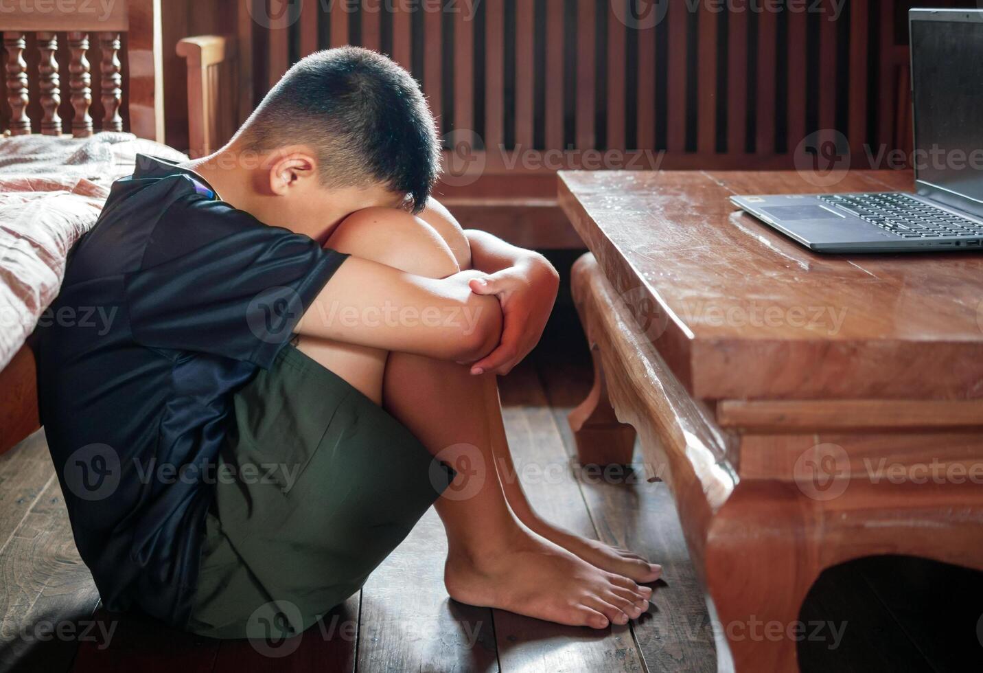 Asian kid boy Upset, sitting in the dark, thinking about conflicts, family relationships. sad face, Unhappy child sitting with head down, Emotion sad and sad face, depression children concept photo