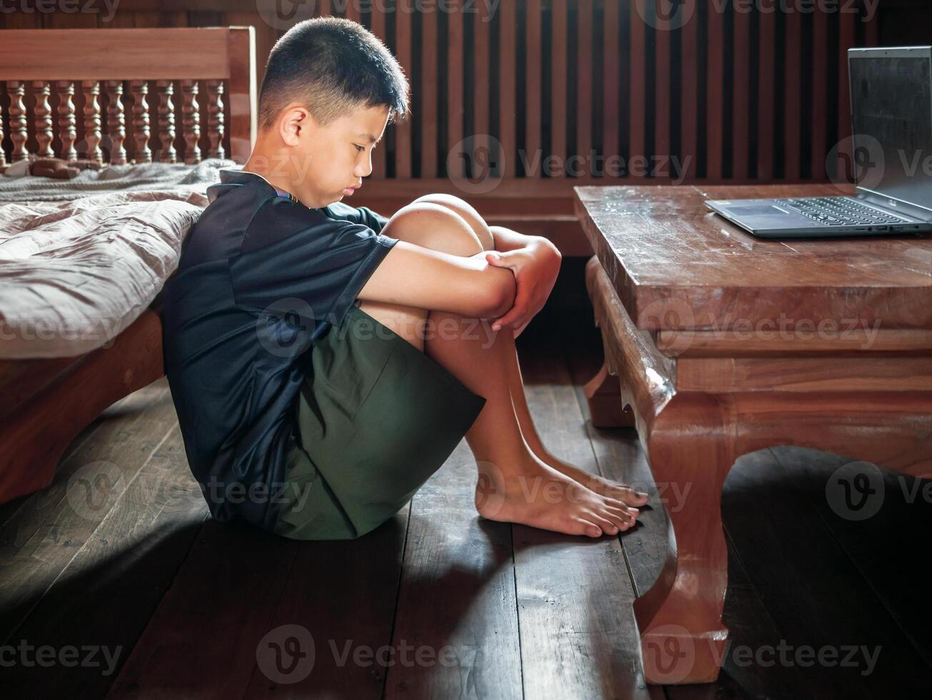 Asian kid boy Upset, sitting in the dark, thinking about conflicts, family relationships. sad face, Unhappy child sitting with head down, Emotion sad and sad face, depression children concept photo