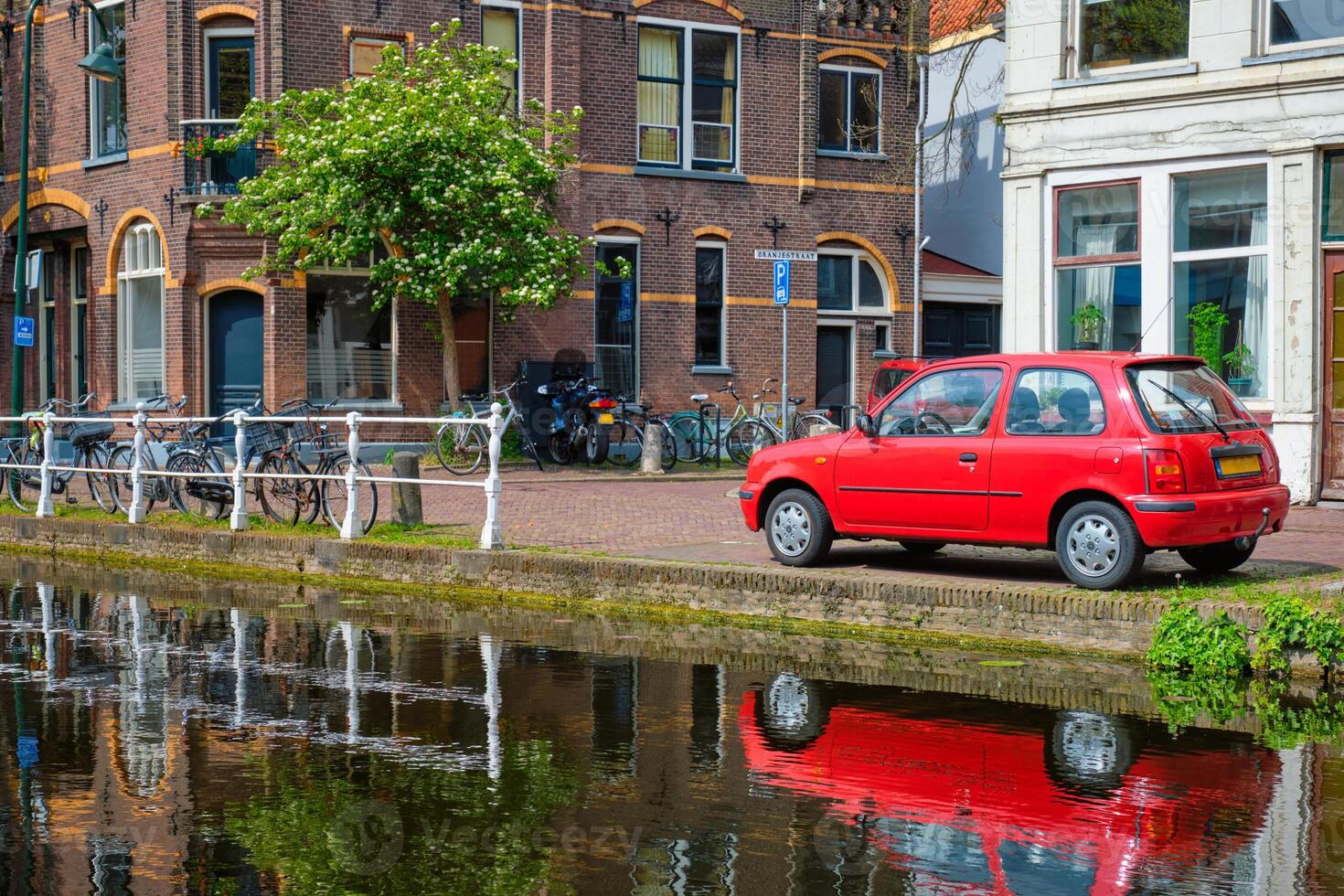 Cars on canal embankment in street of Delft. Delft, Netherlands photo