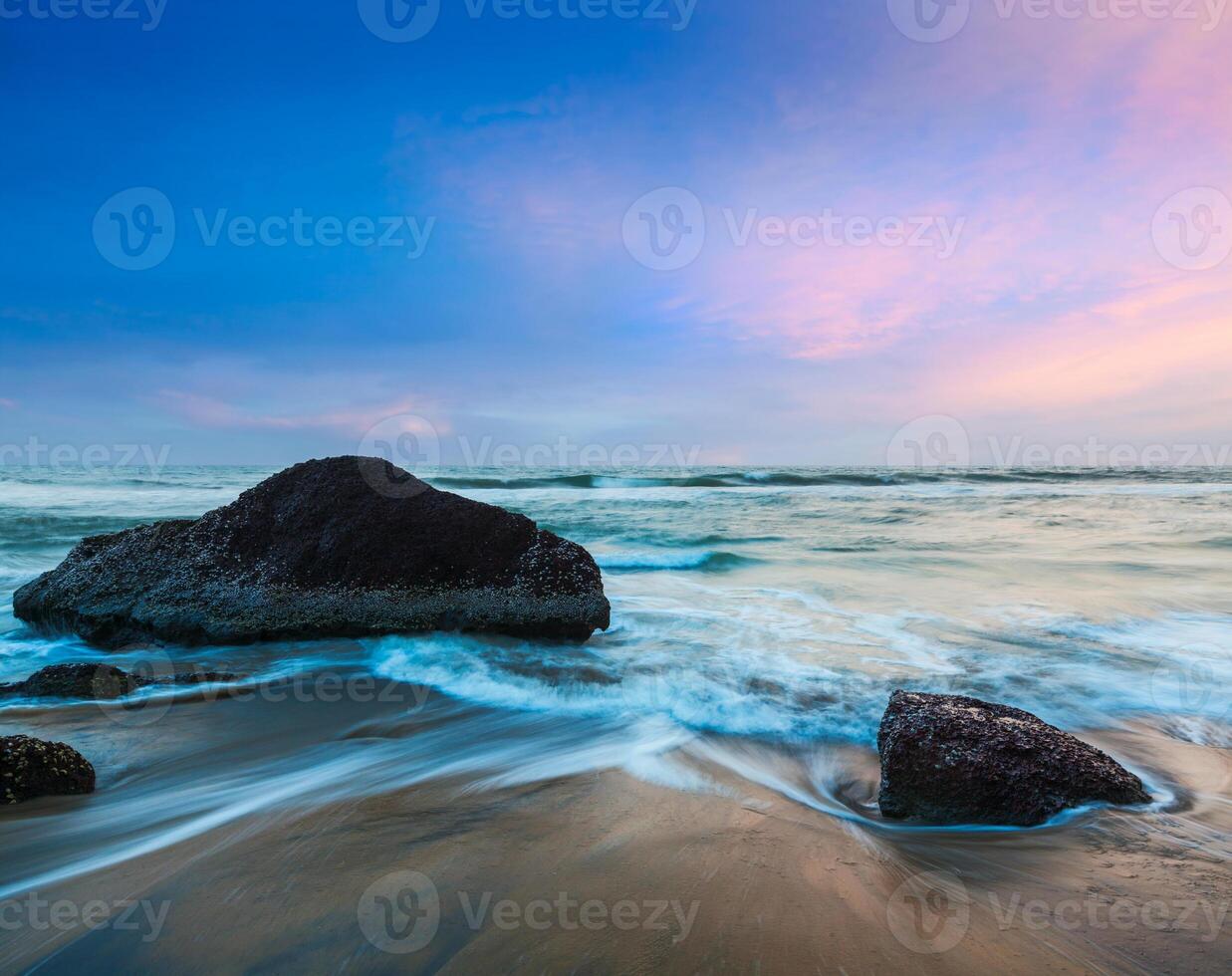 olas y rocas en la playa del atardecer foto