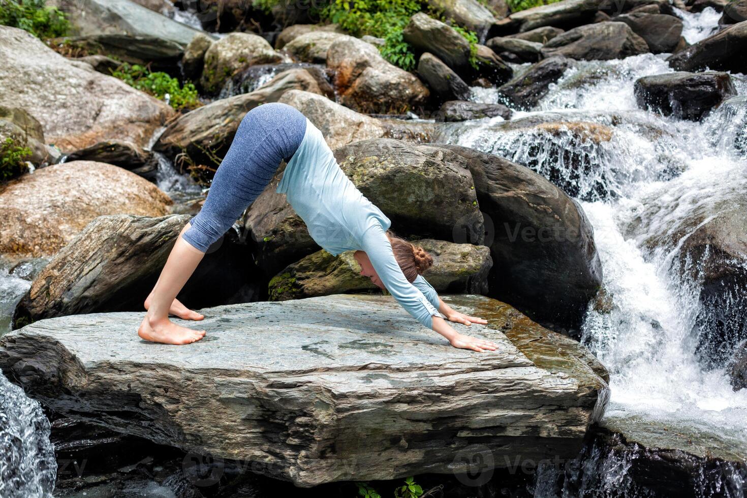 Young fit woman doing yoga oudoors at waterfall photo