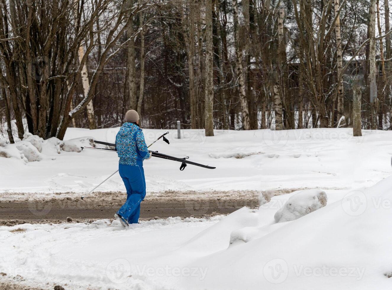 mujer en invierno Deportes traje caminando en Nevado la carretera después esquiar foto