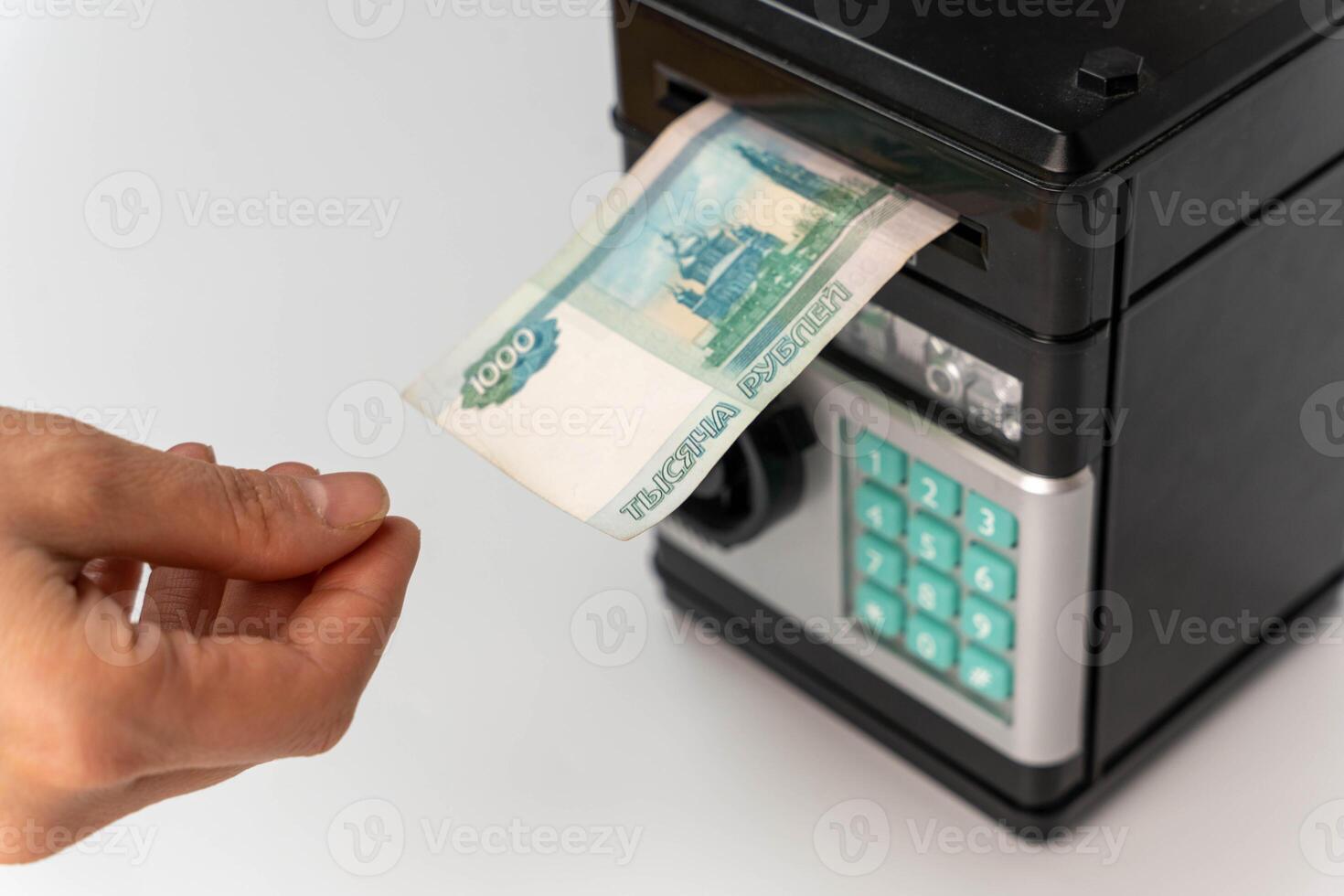 woman's hand puts a 1000 banknote in safe, symbolizing the concept of savings photo
