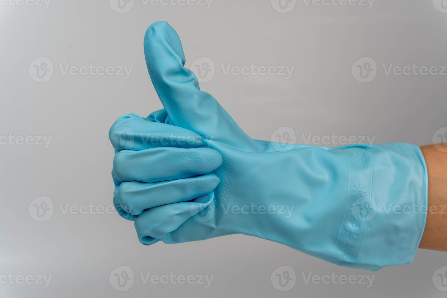 Woman's hand in turquoise rubber gloves showing thumbs up gesture on white background photo