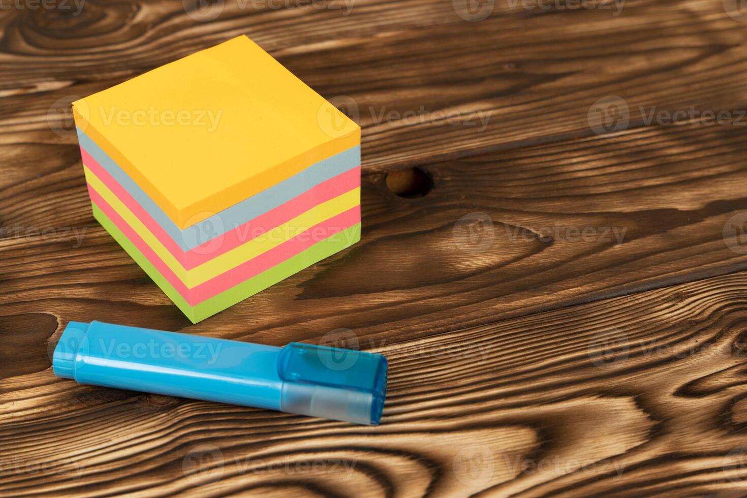 A stack of colorful notes, reminder stickers and a blue marker on a wooden table. organization, planning photo