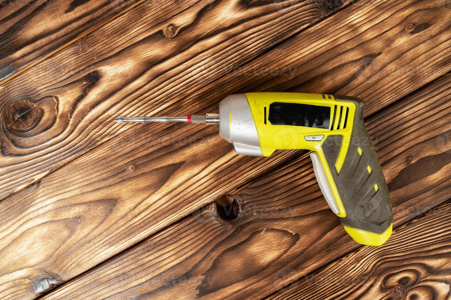 a cordless screwdriver. Cordless drill on a wooden background. DIY concept photo