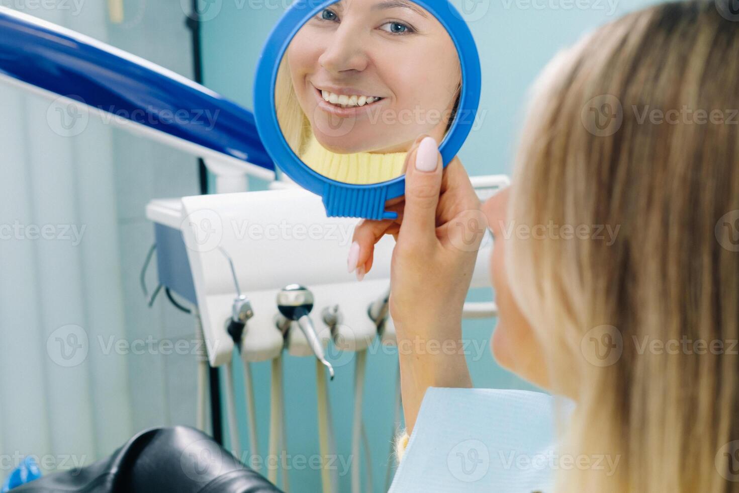 The girl smiles and looks in the mirror in dentistry photo